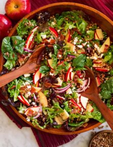 Overhead photo of apple salad in a wooden serving bowl with wooden serving spoons.