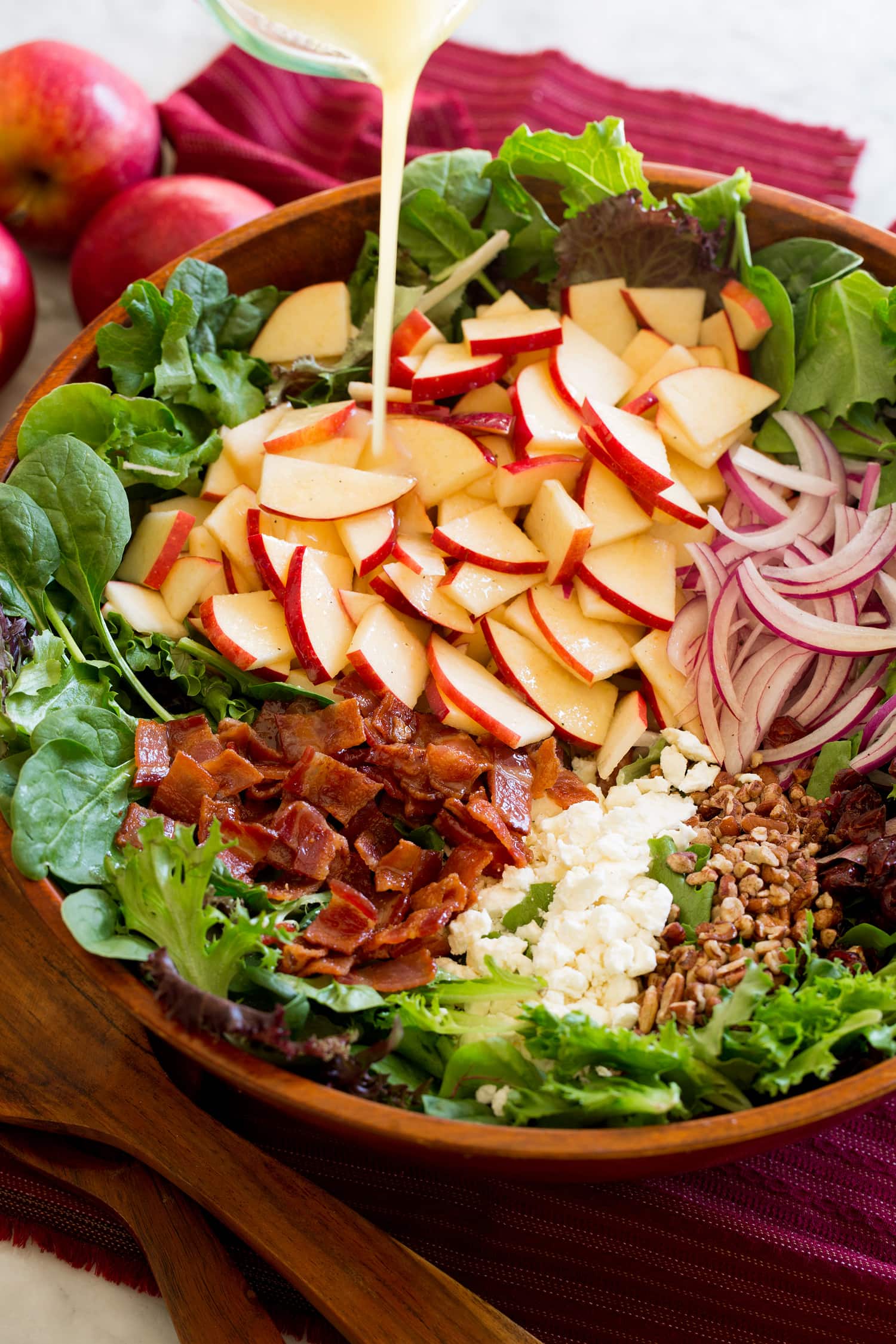 Adding dressing to salad with apples.
