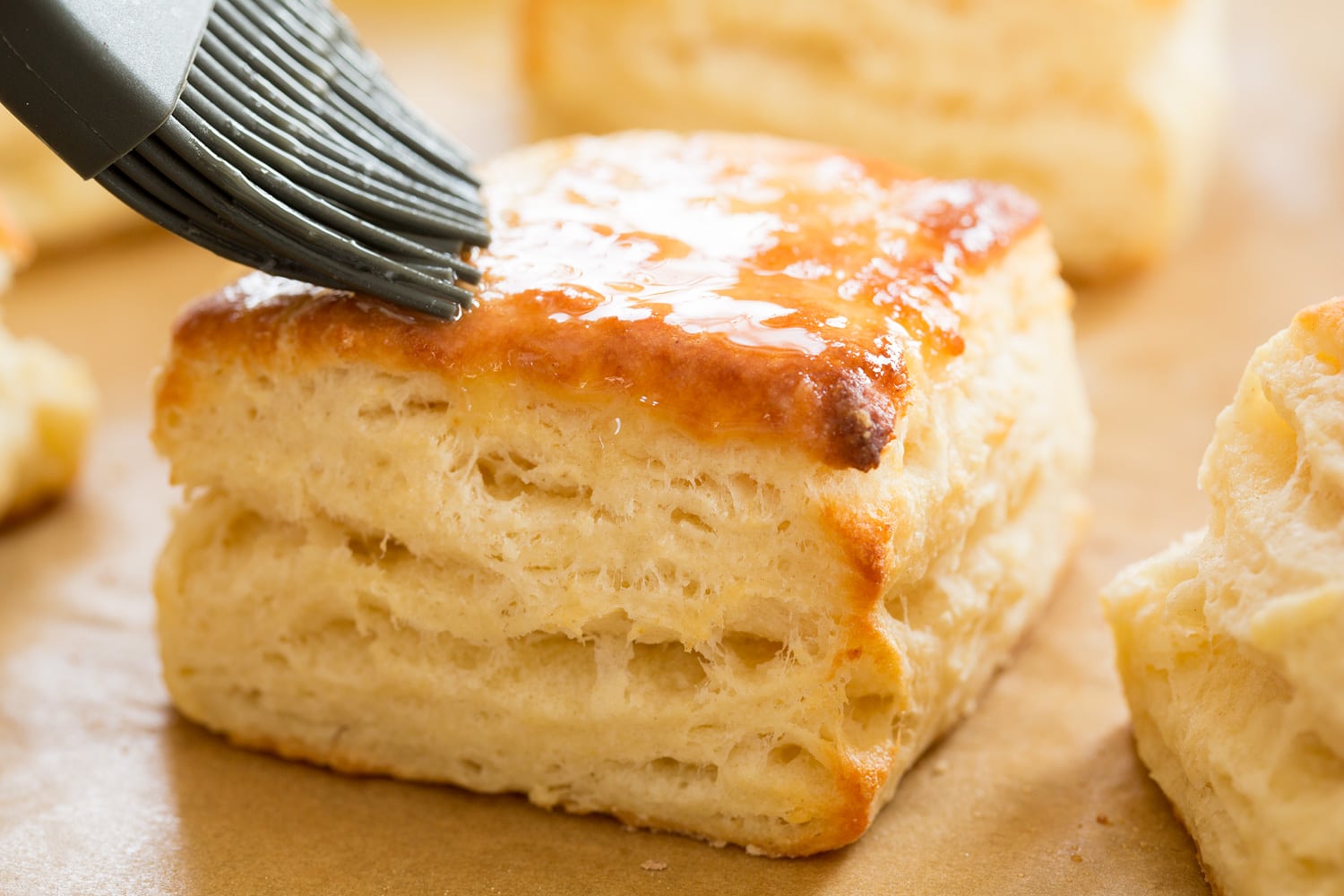 Brushing baked buttermilk biscuits with melted butter.