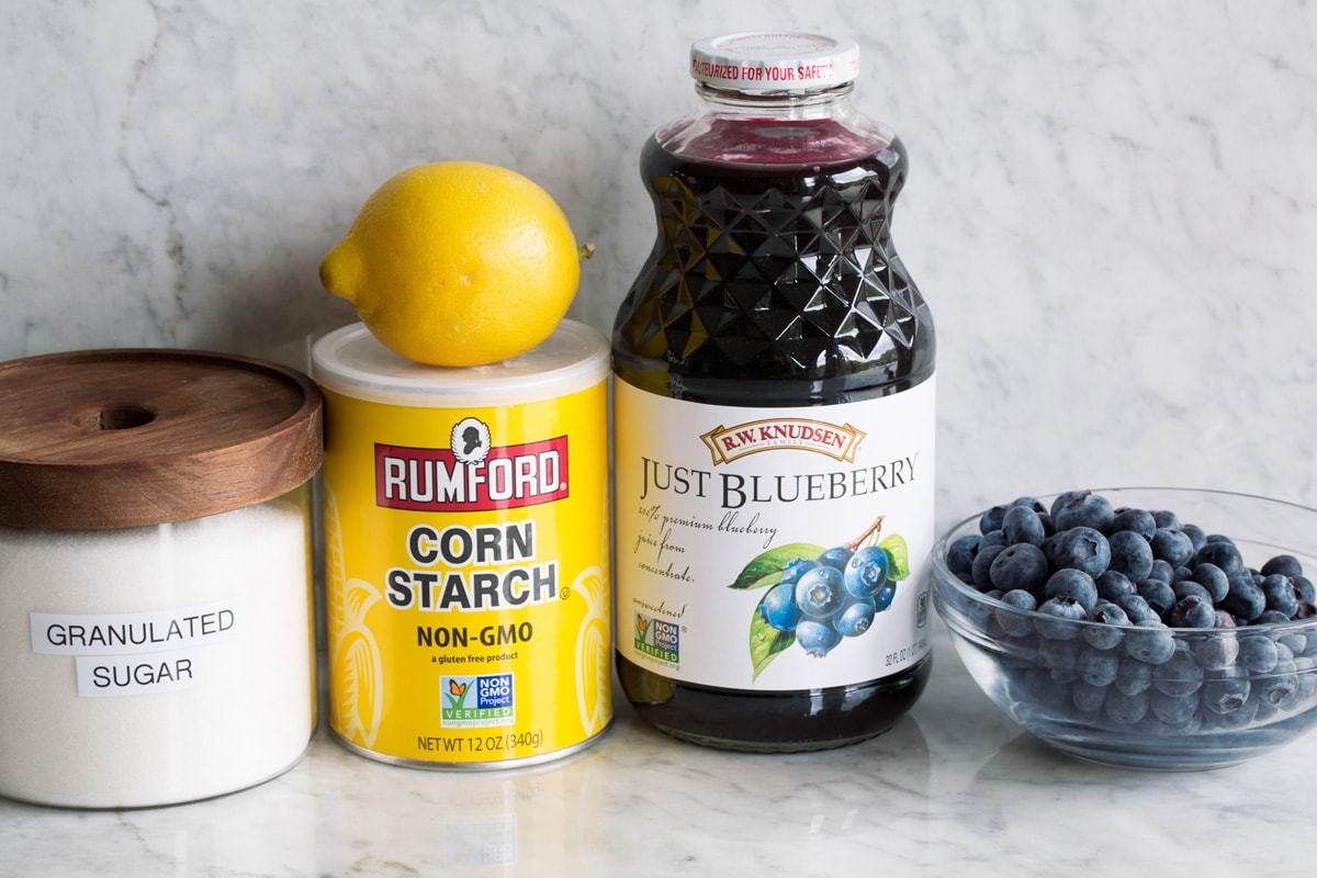 Ingredients used to make blueberry syrup. Includes blueberries, blueberry juice, cornstarch, lemon and sugar.