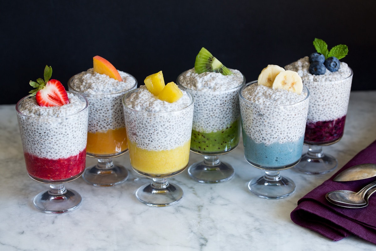 Six jars of chia pudding layered with fruit puree and topped with fresh fruit.