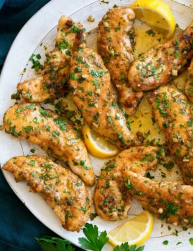 Chicken tenders with a garlic lemon and butter sauce shown on a serving plate.