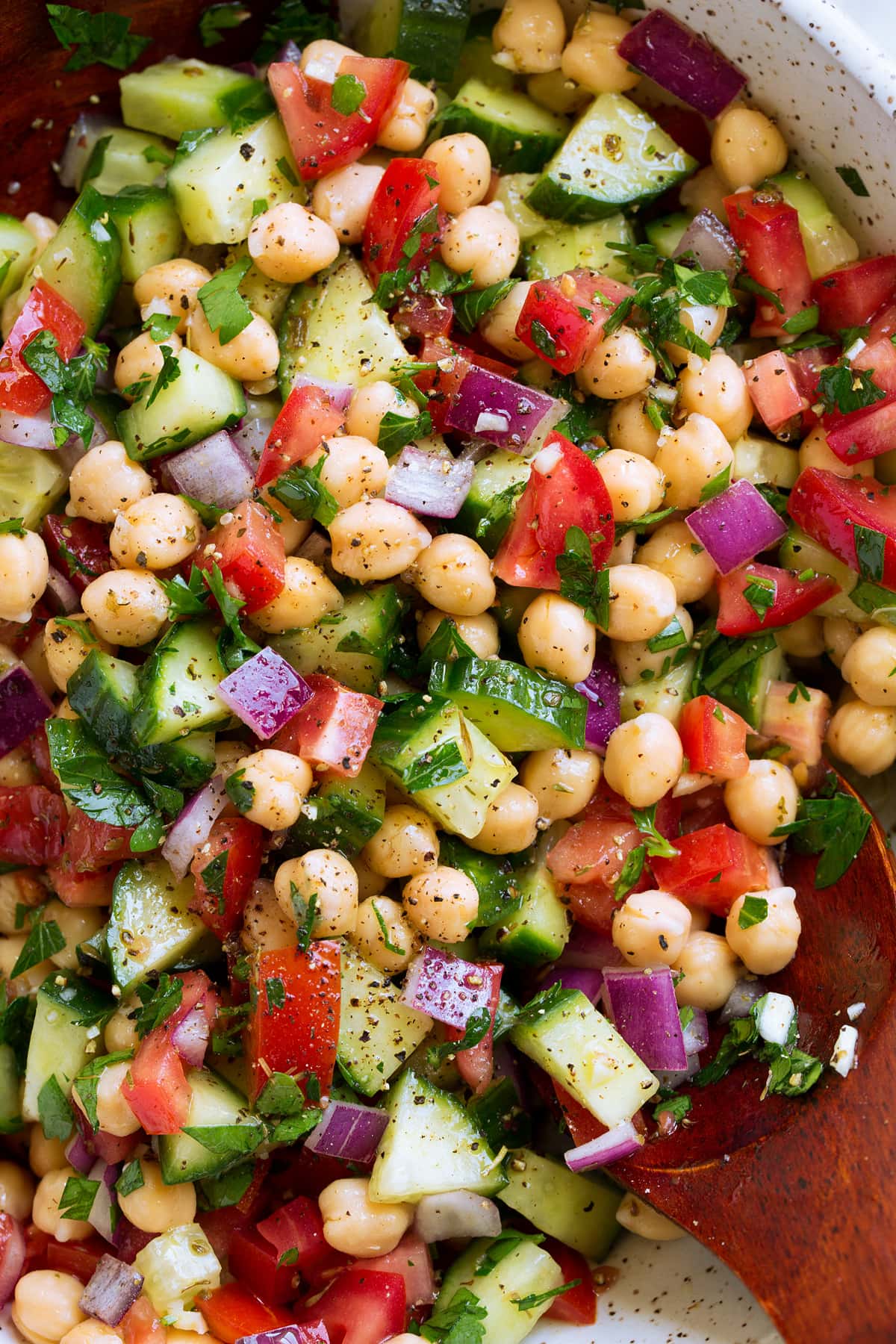 Close up overhead photo of Chickpea Salad with chickpeas, tomatoes, cucumbers, herbs and onion.