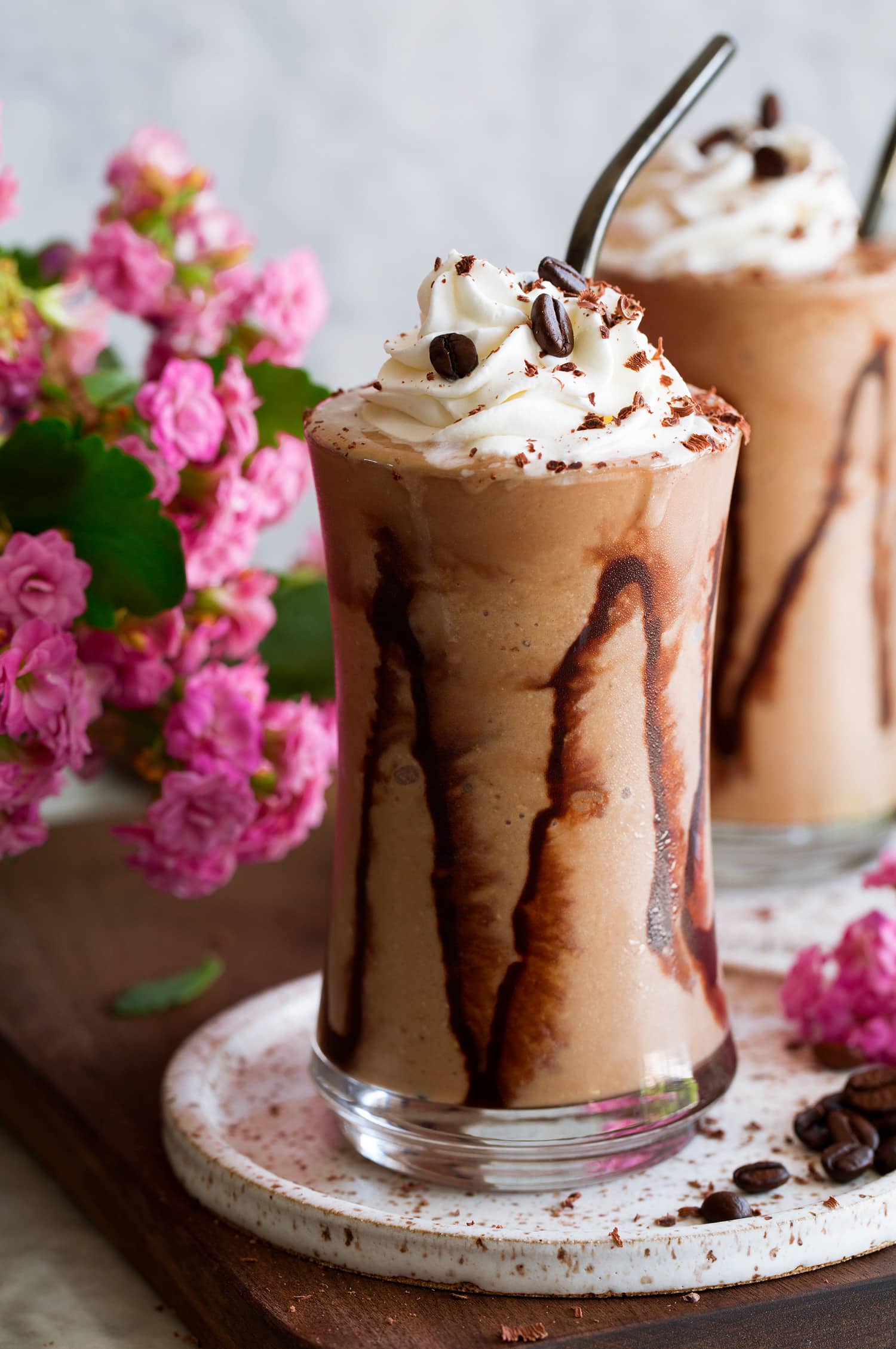 Close up photo of coffee smoothie with streaks of chocolate sauce on glass and whipped cream topping.
