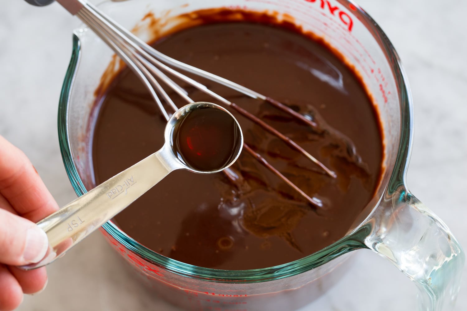 Adding vanilla to fudge sauce.