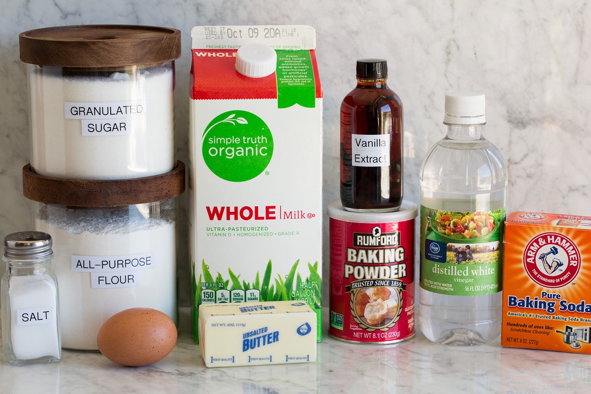 Photo of ingredients for pancakes. Includes milk, flour, sugar, baking soda, baking powder, vinegar, vanilla, sugar, egg and butter.