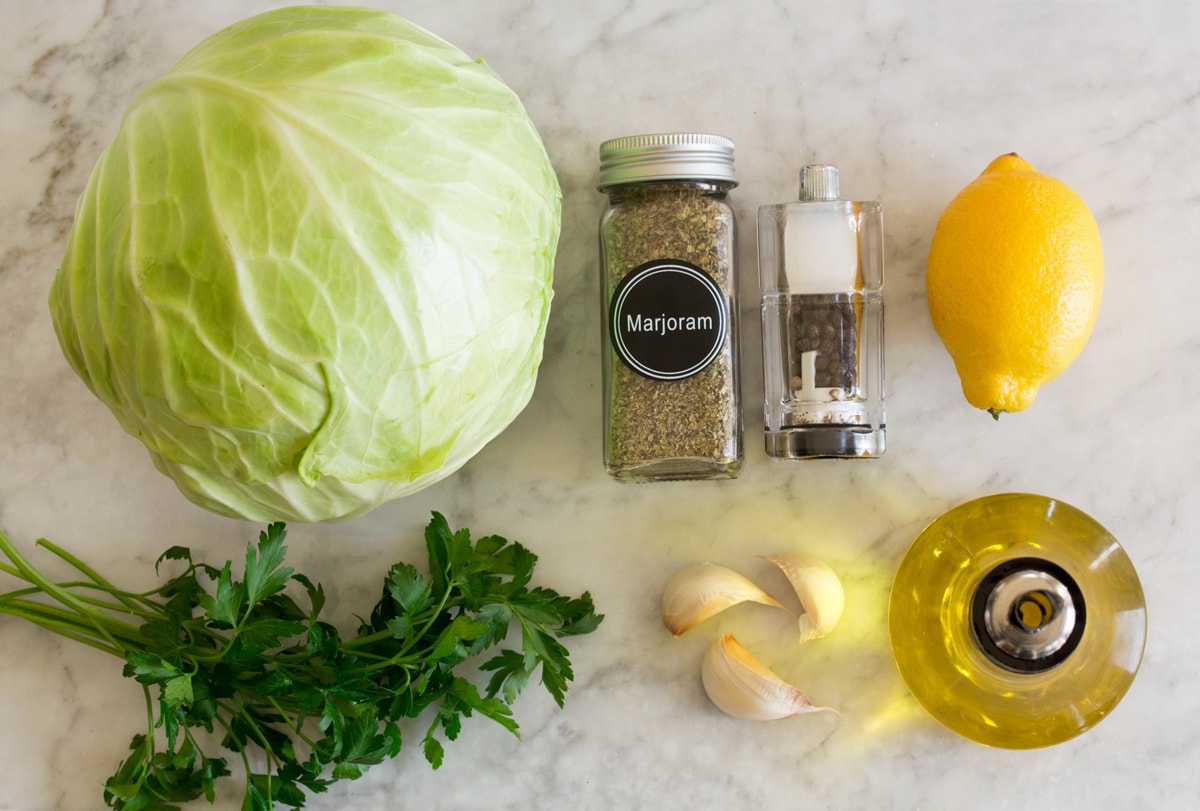 Photo: Ingredients used in making roasted cabbage are shown here. Includes fresh cabbage, olive oil, garlic, parsley, lemon, salt, pepper, and marjarom.