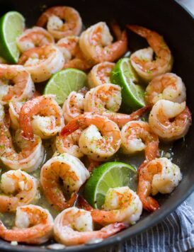 Close up image of shrimp with honey lime sauce in a black skillet.