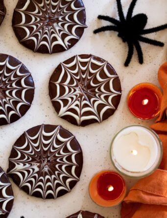 Close up photo showing chocolate spiderweb piping on halloween cookies.